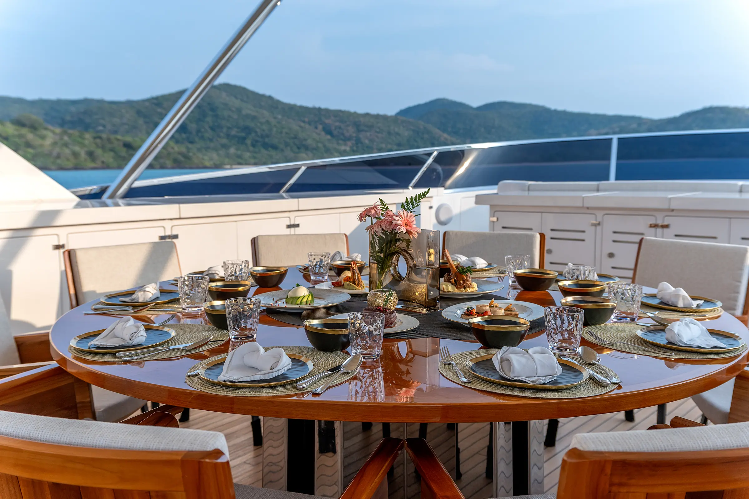 A table laid for dinner on deck, the islands beyond