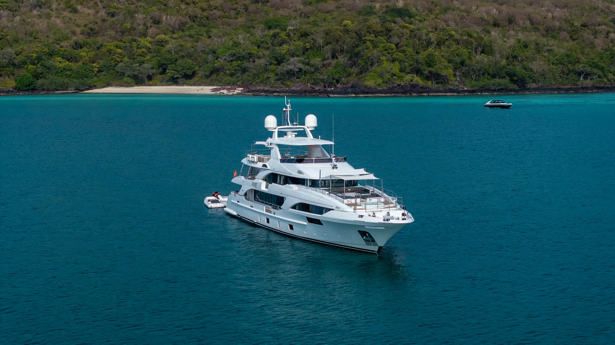 Asia Poseidon at anchor off a wooded headland